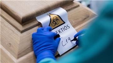 Ein Bestattungsunternehmer schreibt „C19“ auf ein Schild mit dem Hinweis „Infektiös“ auf einen Sarg mit einem Verstorbenen, der an dem Coronavirus gestorben ist.