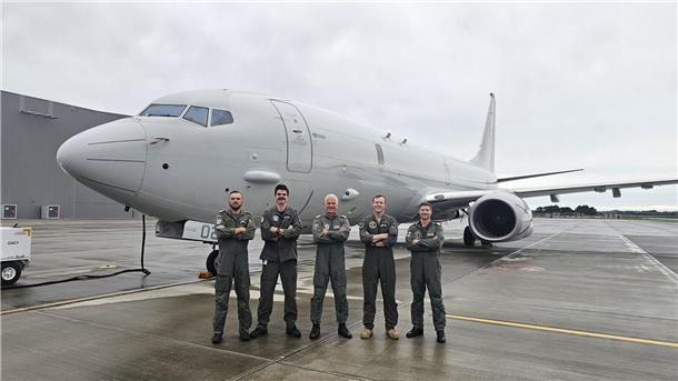 Fünf Männer stehen vor einem Flugzeug.