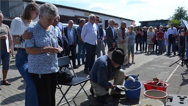 Carla Lucka, gestützt von ihrer Enkelin Joy Rosenberg, gedenkt am 15. Juni im Angesicht der soeben von Gunter Demnig in der Mückenburg verlegten Stolpersteine ihrer Familie der 1942 in Minsk ermordeten Großmutter Klara Wolff, von der sie ein Foto in Händen hält.