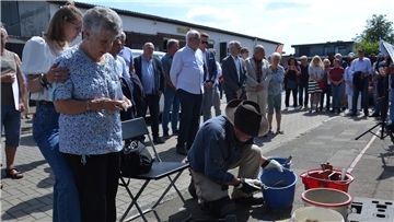 Carla Lucka, gestützt von ihrer Enkelin Joy Rosenberg, gedenkt am 15. Juni im Angesicht der soeben von Gunter Demnig in der Mückenburg verlegten Stolpersteine ihrer Familie der 1942 in Minsk ermordeten Großmutter Klara Wolff, von der sie ein Foto in Händen hält.