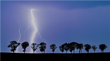 Ein Blitz eines Gewitters erhellt den Nachthimmel über der Landschaft im Osten des Landes Brandenburg.