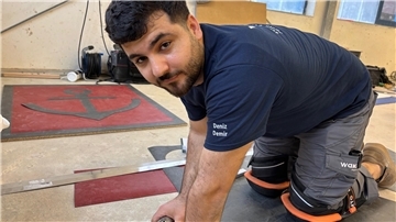 Ein Bodenverleger verbringt viel Zeit auf den Knien: Deniz Demir beim Fertigen der PVC-Platte. 