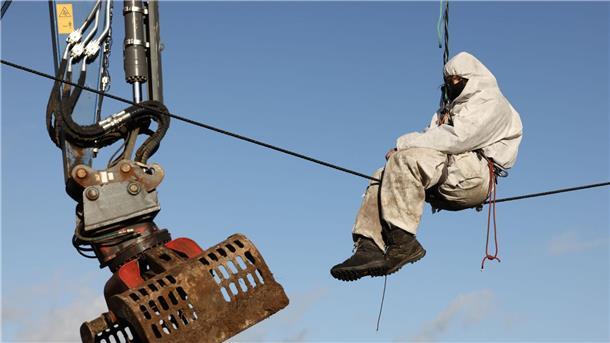 Abrissbagger in Lützerath - Widerstand bröckelt Ein Demonstrant sitzt während der Räumung neben einer Baggerschaufel auf einem Drahtseil.