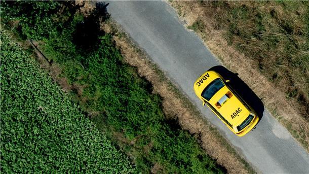 Ein Fahrzeug der ADAC Pannenhilfe fährt über einen Feldweg.