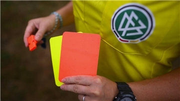 Ein DFB-Schiedsrichter hält eine Rote und eine Gelbe Karte in der Hand.
