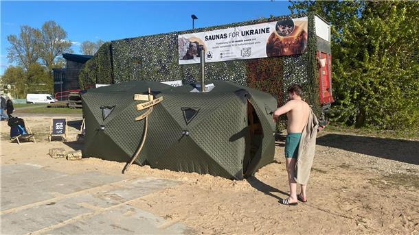 Sauna-Debattenfestival in Kulturhauptstadt Tartu Ein Festival-Besucher steht vor einer mobilen Front-Sauna, die in Estland für die ukrainische Armee entwickelt worden ist.
