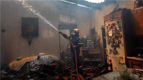 Griechenland kämpft gegen zahlreiche Brände Ein Feuerwehrmann löscht ein Haus im Dorf Hasia in der Nähe von Athen.