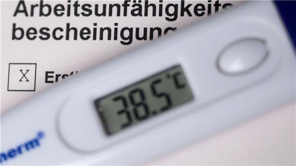 Ein Fieberthermometer liegt auf einer Arbeitsunfähigkeitsbescheinigung.