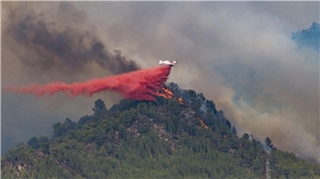 Ein Flugzeug wirft Löschmittel auf die Flammen eines Waldbrandes im spanischen Castellgali.