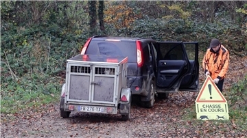 Ein französischer Jäger stellt ein Schild auf, das Spaziergänger vor einer Drückjagd warnt.