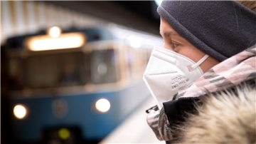 Ein Frau mit FFP2-Maske wartet auf die Bahn.