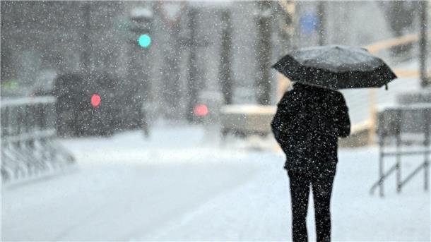 Ein Fußgänger geht mit einem Schirm durch das Schneetreiben in Köln.
