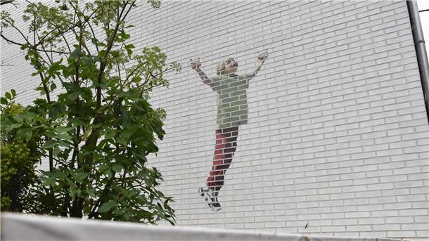Ein Gedenkgarten soll an die getöteten Kinder erinnern. An einer Hauswand: Ein Kind, das einen Drachen steigen lässt.