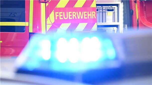 Im Vordergrund Blaulicht und im Hintergrund ein Fahrzeug mit der Aufschrift Feuerwehr.