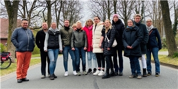 Männer und Frauen blicken in die Kamera.