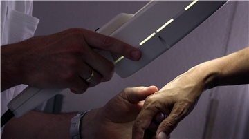 Ein Hautarzt untersucht mit einem Vergrößerungsglas die Haut einer Patientin bei einer Hautkrebs-Früherkennung. Das fand wegen Corona deutlich weniger statt.