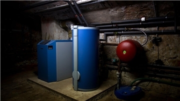 Ein Heizkessel und ein Warmwasserboiler stehen in einem Heizkeller in Dresden.
