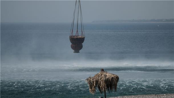 Griechische Feuerwehr: Brände größtenteils unter Kontrolle Ein Hubschrauber füllt in der Nähe des Dorfes Gennadi einen Korb mit Wasser aus dem Meer auf.