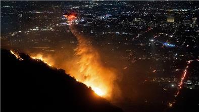 Ein Hubschrauber wirft Wasser auf das brennende Sunset Fire in den Hollywood Hills.