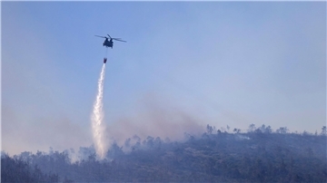 Ein Hubschrauber wirft Wasser auf einen Waldbrand im Norden Athens ab.