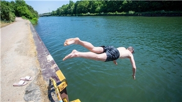 Ein junger Mann springt bei hochsommerlichem Wetter in den Rhein-Herne-Kanal.
