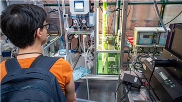 Studieninteressierte vor einem Bioreaktor mit Mikroalgen bei der Hochschule Bremerhaven.
