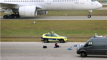 Ein Klimaaktivist sitzt mit angeklebter Hand auf dem Start-und Landebahn am Airport Franz-Josef-Strauß in München.