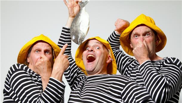 Drei Männer, einer hat einen Fisch in der Hand