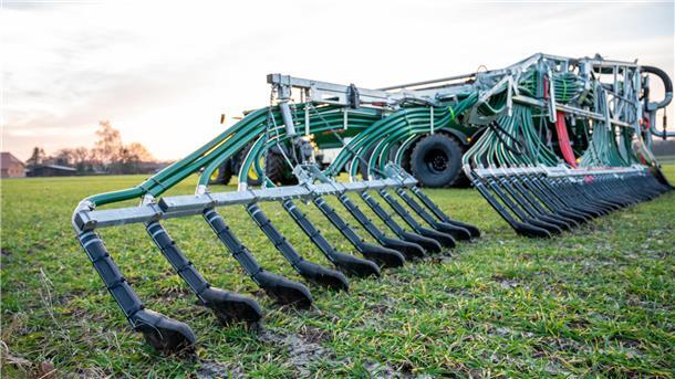 Ein Landwirt bringt mit seinem Gespann Gülle auf einem Feld aus
