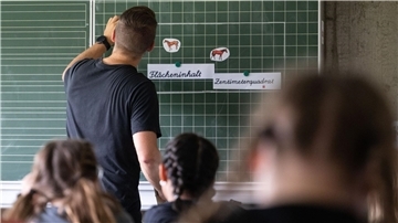 Ein Lehrer steht vorn im Klassenraum. Für gewöhnlich siezt man den.