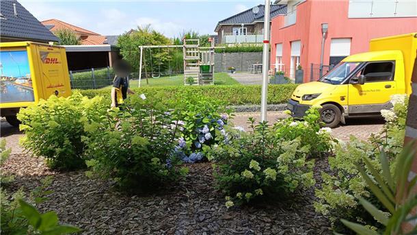 Zustellerin mit Paketlieferfahrzeugen in einer Wohnstraße