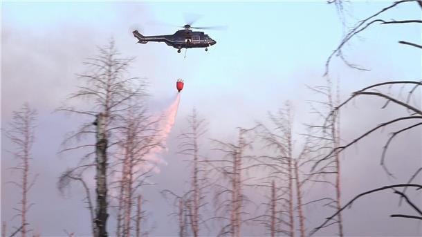 Waldbrand bei Jüterbog weitet sich aus Ein Löschhubschrauber über dem Waldbrand in einem munitionsbelasteten Gebiet bei Jüterbog (Landkreis Teltow-Fläming).