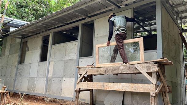 Gebrauchte Windeln können Baumaterial von Häusern ersetzen Ein Mann arbeitet am Rohbau eines einfachen Hauses, bei dem gebrauchte Windeln einen Teil des Baumaterials ersetzen.