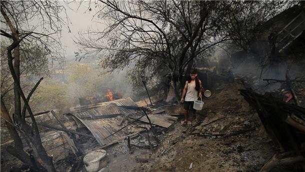 Ein Mann geht an einem Haus vorbei, das bei einem Waldbrand in der algerischen Provinz Bouira niedergebrannt ist.