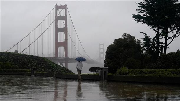 Tornados und Todesopfer nach Überschwemmungen in den USA Ein Mann geht bei Regen an der Golden Gate Bridge vorbei, dem Wahrzeichen von San Francisco.