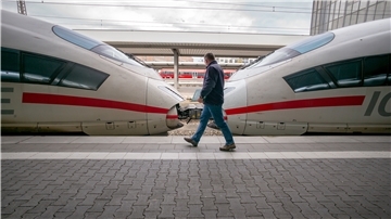 Ein Mann läuft über ein Bahnsteig, an dem ein ICE steht.
