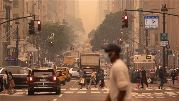 Rauch von Waldbränden hüllt New York ein Ein Mann mit FFP2-Maske überquert eine Kreuzung in Manhattan.