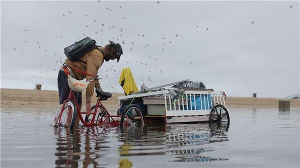 Bilder des Tages Ein Mann passt seine Ladung auf dem Fahrradanhänger an, um den durch heftigen Regenfällen überfluteten Weg entlang zufahren.