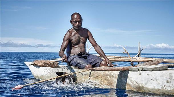 Papua-Neuguinea: Haie anlocken mit uralten Liedern Ein Mann sitzt beim „Shark Calling Festival“ in einem Boot. Auf der Insel vor Papua-Neuguinea rufen Einheimische gefährliche Haie mit Liedern und Rasseln.