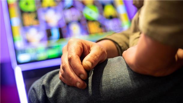 Ein Mann sitzt in einer Kneipe an einem Spielautomat.