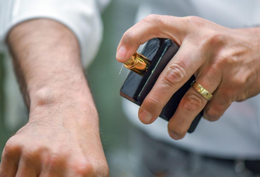 Wenn der Gast einem stinkt: Tut ein Duft-Dresscode not? Ein Mann sprüht sich Parfum auf die Hand - Experten geben den Tipp: An Stellen, die gut durchblutet sind (zum Beispiel hinter den Ohren, am Puls oder der Armbeuge), wirken Düfte besonders intensiv. (Archivbild)