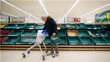 Ein Mann steht vor einem leeren Gemüseregal in einem Supermarkt in Manchester.