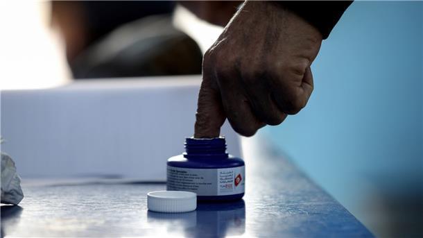 Ein Mann taucht seinen Finger in Tinte bei seiner Stimmabgabe in einem Wahllokal für die tunesischen Parlamentswahlen 2022.