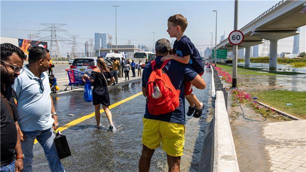 Nach Unwetter in Dubai weiter Störungen am Flughafen Ein Mann trägt ein Kind durch das von starkem Regen verursachte Hochwasser in Dubai.