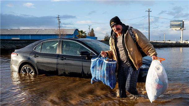 Extremwetter-Jahr: Von Wassermassen und Wirbelstürmen Ein Mann trägt im Januar in Merced, Kalifornien, Habseligkeiten aus seinem überfluteten Haus.