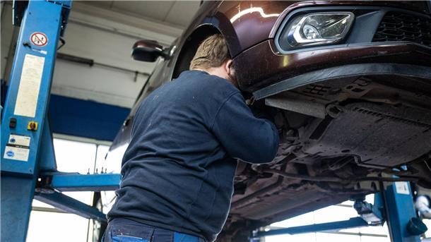 Autoreparatur-Studie: Neue Ersatzteile schlecht fürs Klima Ein Mechaniker schaut in einer Kfz-Werkstatt in den Radkasten eines Autos.