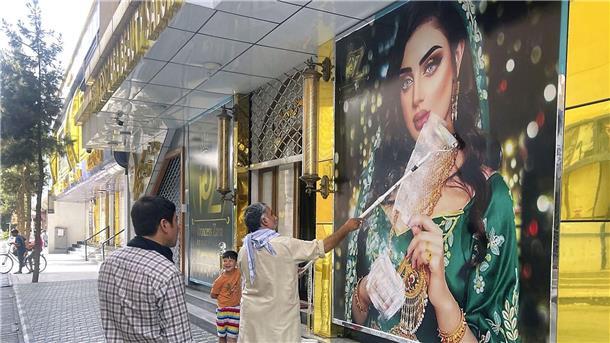 Ein Mitarbeiter eines Schönheitssalons übermalt nach der Machtübernahme der Taliban das Bild einer Frau in Kabul (Archivbild). Frauen haben in der afghanischen Hauptstadt gegen die Schließung der Salons protestiert.