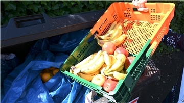 Ein Mitarbeiter eines Supermarktes bringt Obst zu einem Müllcontainer.