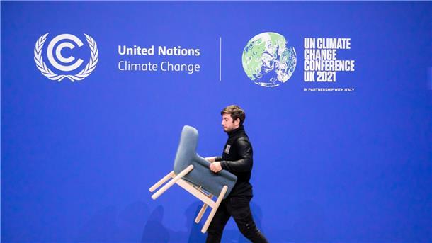 Was aus den Zusagen zum Klimaschutz von Glasgow wurde Ein Mitarbeiter trägt bei der UN-Klimakonferenz COP26 einen Stuhl von einer Bühne.