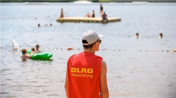 DLRG: So viele vor Ertrinken gerettet wie lange nicht Ein Mitglied der Deutschen Lebens-Rettungs-Gesellschaft (DLRG) steht in einem Strandbad am Ufer.